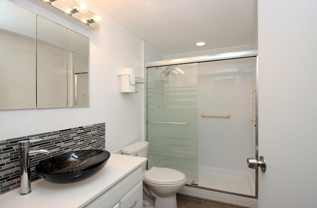 bathroom featuring toilet, a shower stall, vanity, and decorative backsplash