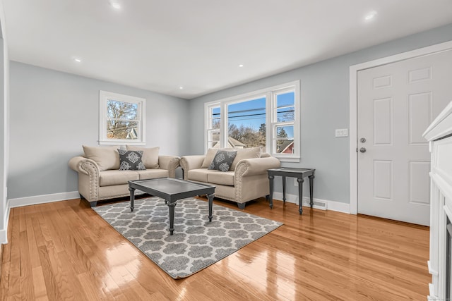 living room with light wood-style flooring, baseboards, and a wealth of natural light