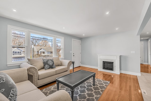 living room featuring baseboards, a premium fireplace, wood finished floors, and recessed lighting