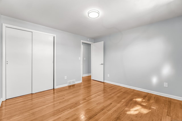 unfurnished bedroom featuring light wood finished floors, visible vents, baseboards, and a closet