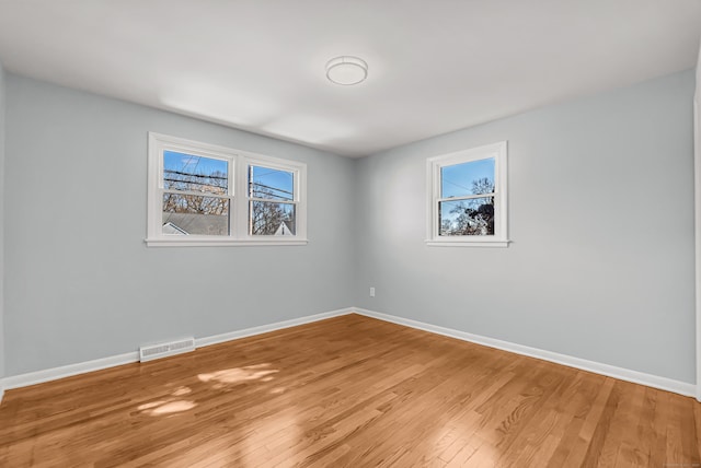 unfurnished room featuring light wood-type flooring, visible vents, and baseboards