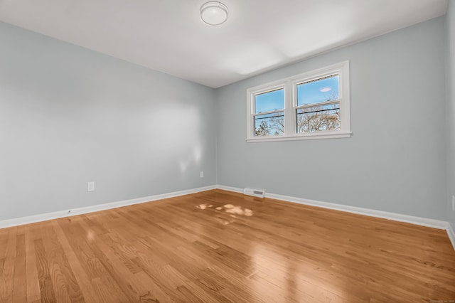 spare room featuring light wood-type flooring, visible vents, and baseboards