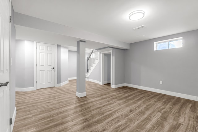 below grade area featuring stairway, wood finished floors, visible vents, and baseboards