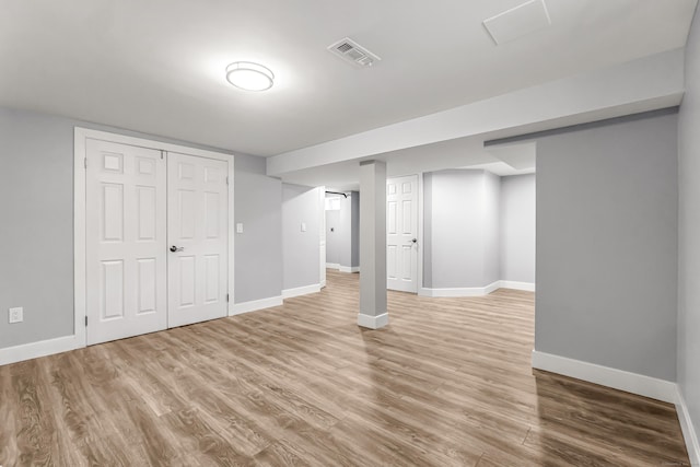 finished below grade area featuring baseboards, visible vents, and wood finished floors