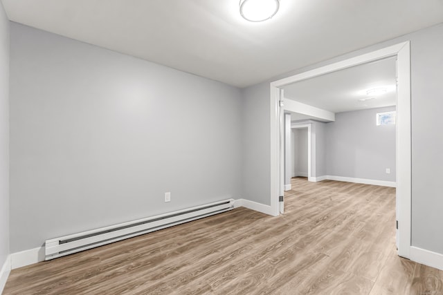 empty room with light wood-type flooring, a baseboard radiator, and baseboards