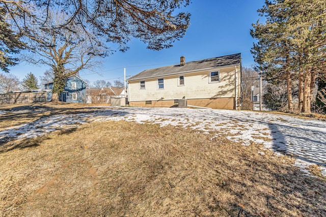 rear view of house featuring a chimney, central AC unit, and a yard