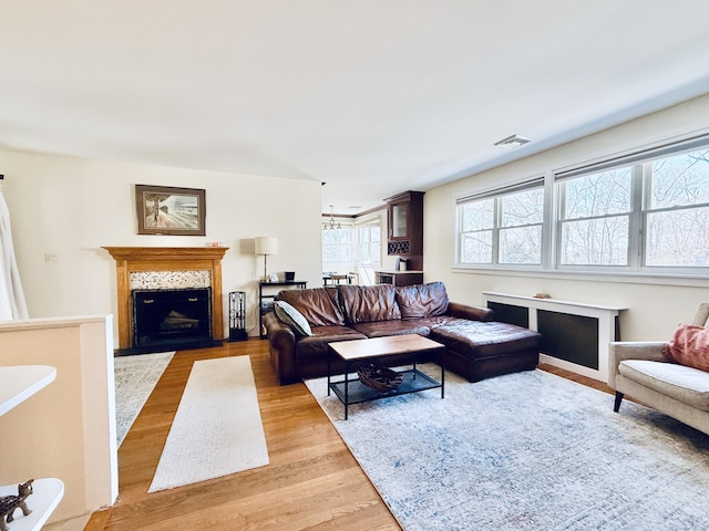 living area with visible vents, a tiled fireplace, and wood finished floors