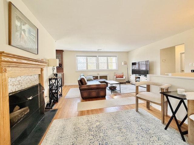 living room with a tile fireplace and light wood-style flooring