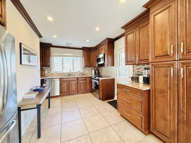 kitchen featuring appliances with stainless steel finishes, crown molding, a healthy amount of sunlight, a sink, and light tile patterned flooring