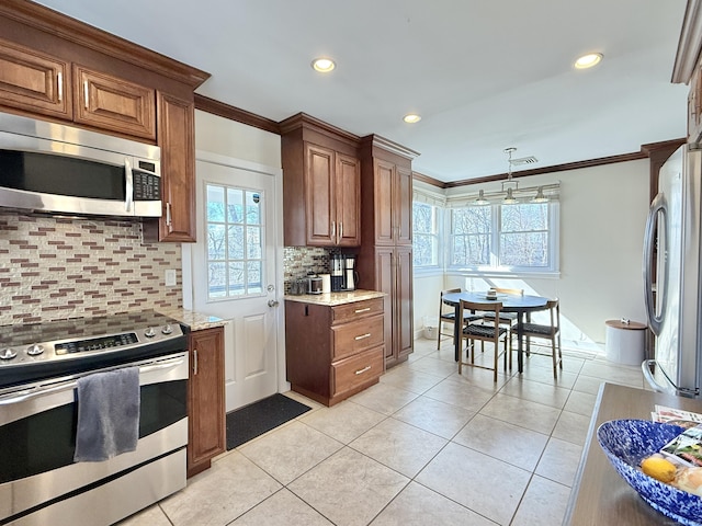 kitchen with light tile patterned floors, light stone counters, stainless steel appliances, visible vents, and ornamental molding