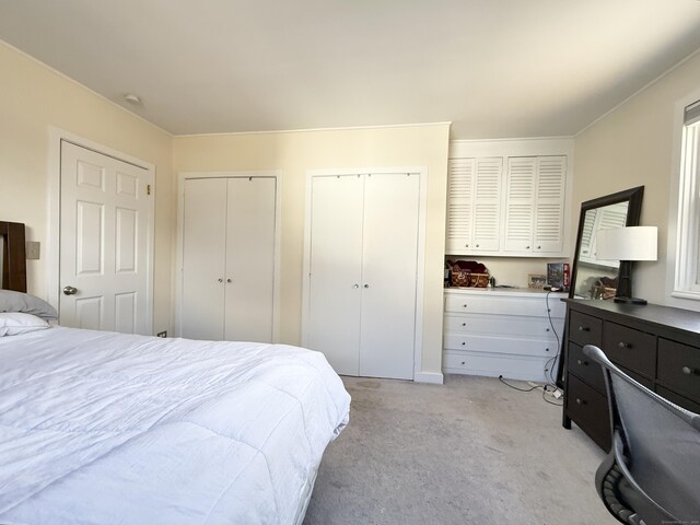 bedroom featuring two closets and light colored carpet