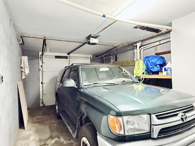 garage featuring concrete block wall and a garage door opener