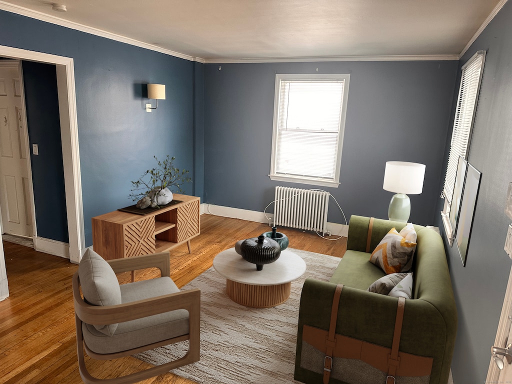 living area featuring ornamental molding, radiator heating unit, wood finished floors, and baseboards