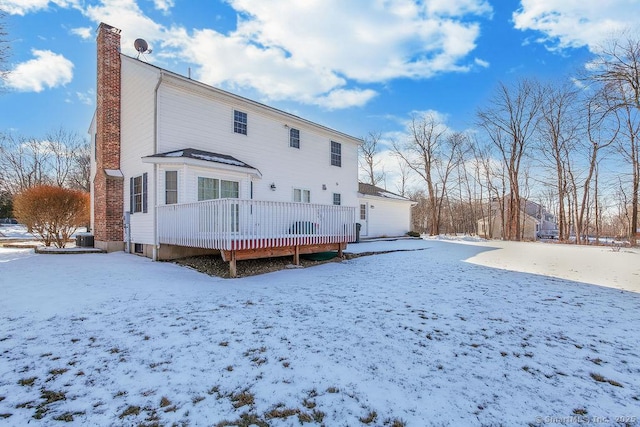 snow covered back of property featuring a chimney and a wooden deck