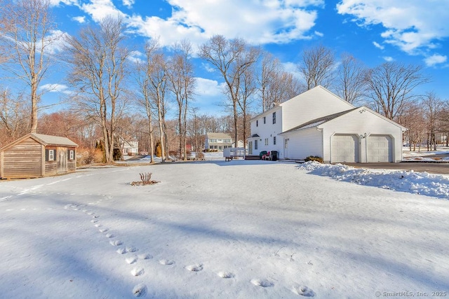 snow covered property featuring an outbuilding and an attached garage