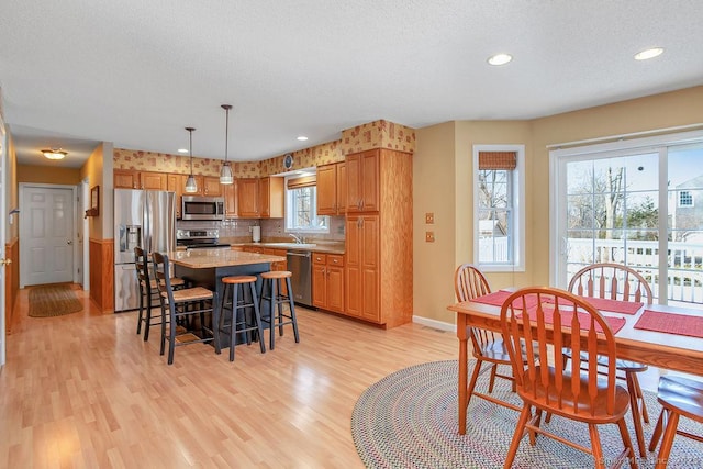 dining room with light wood-type flooring, baseboards, a textured ceiling, and recessed lighting