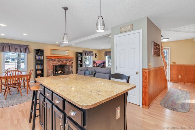 kitchen featuring pendant lighting, wainscoting, light wood-style flooring, and a textured ceiling