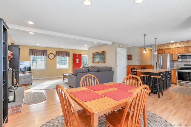 dining space with recessed lighting, baseboards, a textured ceiling, and light wood finished floors