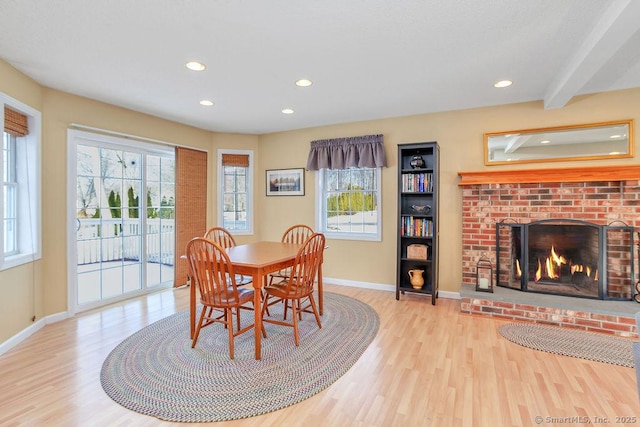 dining space featuring a healthy amount of sunlight, a fireplace, and wood finished floors