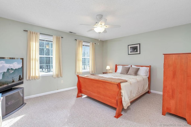 carpeted bedroom featuring a ceiling fan, baseboards, visible vents, and a textured ceiling