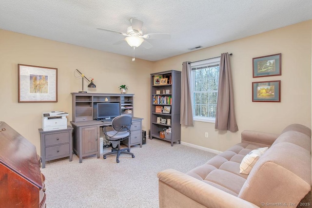 home office with visible vents, light carpet, ceiling fan, a textured ceiling, and baseboards