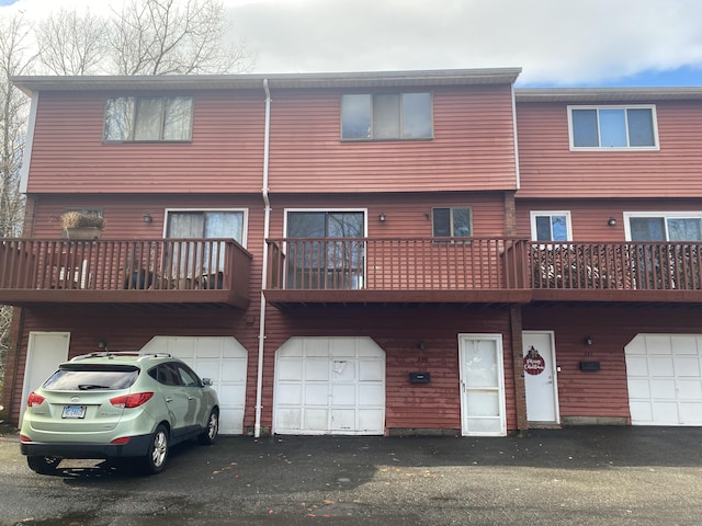 rear view of property featuring driveway and an attached garage