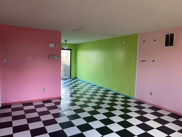 spare room featuring visible vents, a textured ceiling, and tile patterned floors