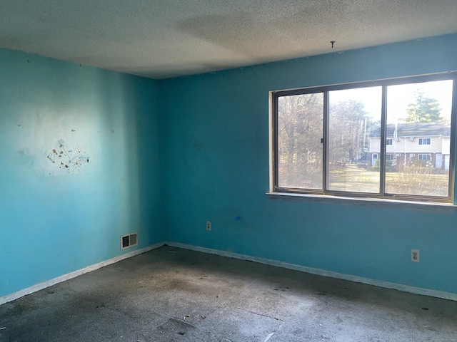 unfurnished room with baseboards, visible vents, and a textured ceiling