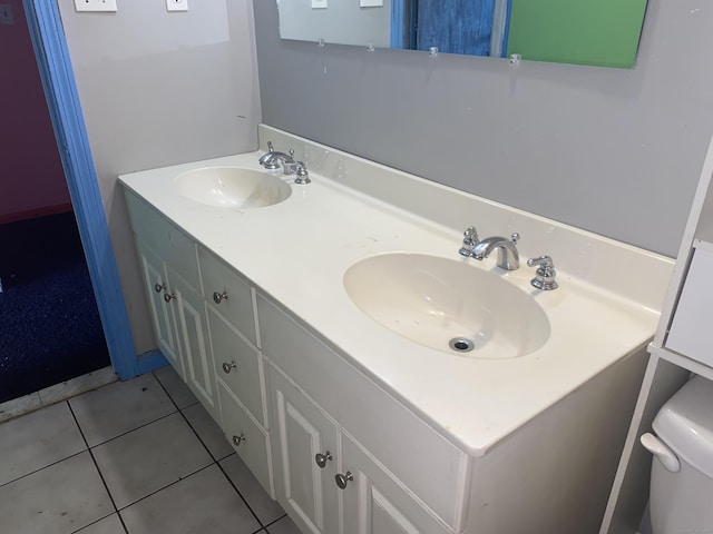 bathroom with toilet, tile patterned flooring, double vanity, and a sink