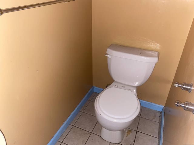 bathroom with baseboards, toilet, and tile patterned floors