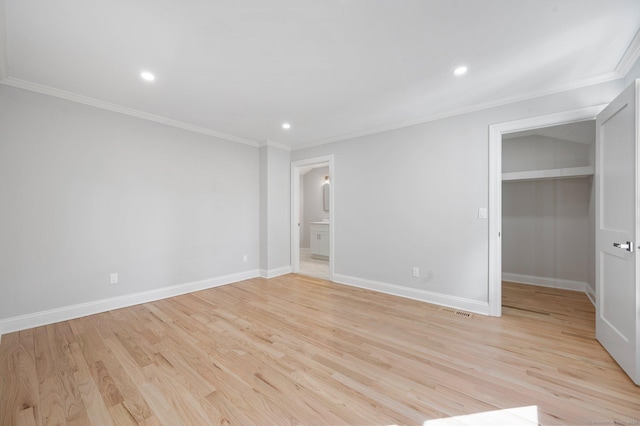 unfurnished bedroom with recessed lighting, baseboards, ornamental molding, light wood-type flooring, and a walk in closet