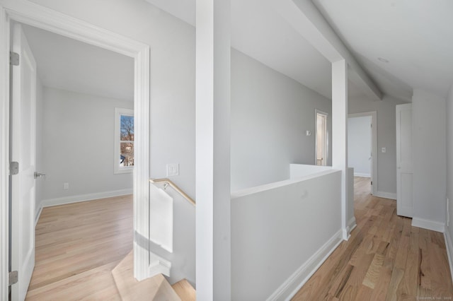 hall with baseboards, light wood finished floors, and an upstairs landing