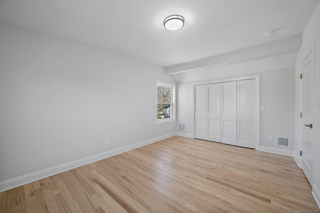 unfurnished bedroom with light wood-type flooring, a closet, visible vents, and baseboards