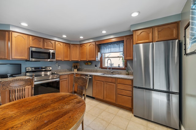 kitchen featuring brown cabinets, stainless steel appliances, a sink, and recessed lighting