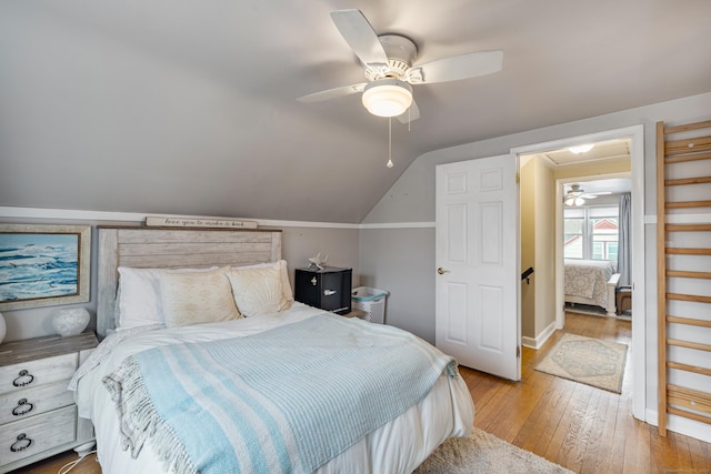 bedroom with hardwood / wood-style flooring, vaulted ceiling, and a ceiling fan