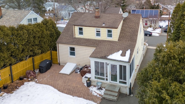 back of house with a shingled roof, a residential view, fence, and a chimney