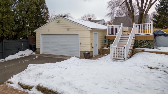 snow covered garage with a detached garage and fence