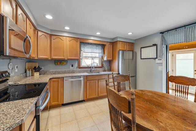 kitchen with light tile patterned flooring, recessed lighting, a sink, appliances with stainless steel finishes, and light stone countertops