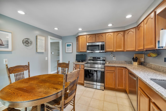 kitchen featuring light tile patterned floors, appliances with stainless steel finishes, light stone counters, and recessed lighting