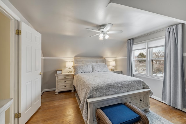 bedroom with vaulted ceiling, baseboards, and light wood-style floors