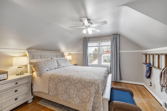 bedroom featuring lofted ceiling, baseboards, visible vents, and wood finished floors