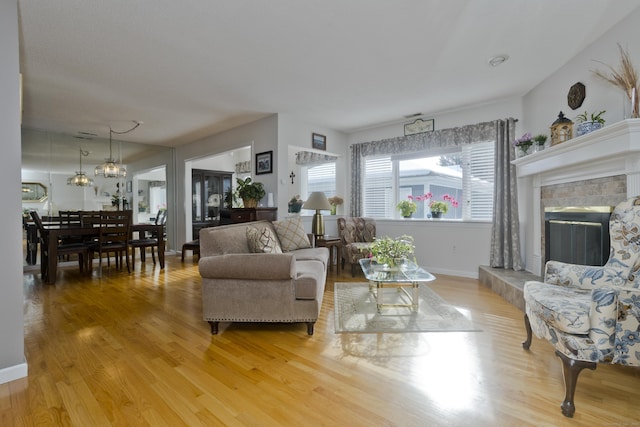 living area with a tile fireplace, light wood-style flooring, and baseboards