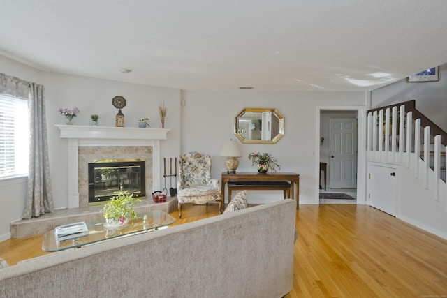 unfurnished living room with stairway, a fireplace, wood finished floors, and baseboards