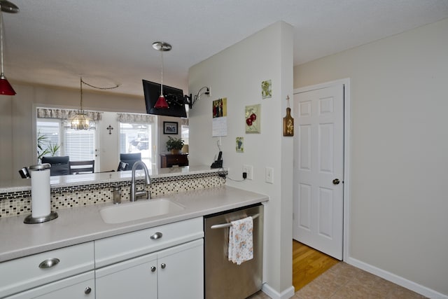 kitchen featuring light countertops, stainless steel dishwasher, a sink, and white cabinetry