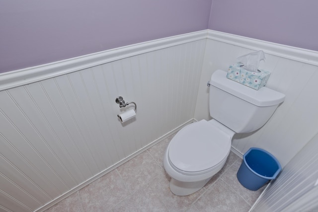 bathroom featuring toilet, a wainscoted wall, and tile patterned flooring