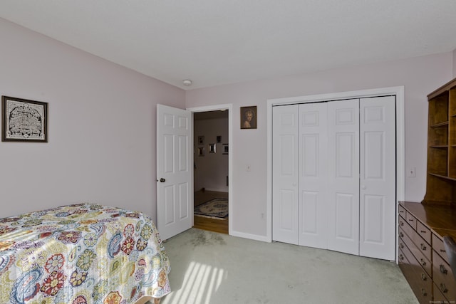 bedroom with a closet, light carpet, and baseboards