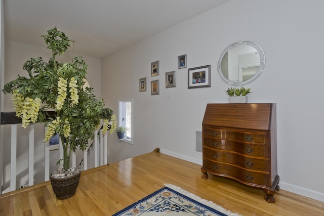 living area with an upstairs landing, wood finished floors, visible vents, and baseboards