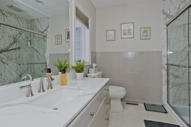 bathroom featuring tile walls, a marble finish shower, visible vents, toilet, and vanity