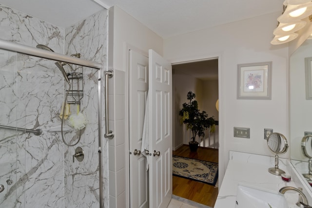 bathroom featuring a marble finish shower, a sink, and wood finished floors