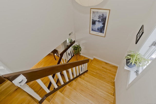 stairway with a healthy amount of sunlight, wood finished floors, visible vents, and baseboards